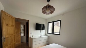 A bedroom with a bed, a dresser, a TV, and a window.