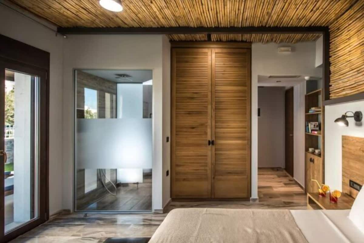 Un dormitorio moderno con una cama grande, un armario de madera y un ventanal que da a un balcón.