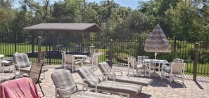 Une terrasse extérieure avec des chaises longues, une table et un parasol.