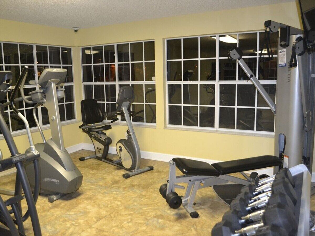 Une salle de sport équipée de machines de cardio, de bancs de musculation et d’haltères.