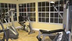 Un gimnasio con máquinas de cardio, bancos para pesas y mancuernas.