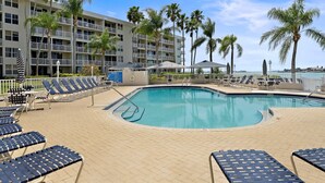 A hotel pool area with sun loungers, palm trees, and a building with balconies. - Isla Del Sol |9-222|2BD 2BA| Amazing View (Isla Del Sol)