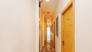 A hallway with a wooden door labeled "105" and a marble floor. - Hotel Priceless Suite (Mumbai)