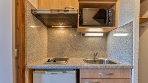 Una cocina compacta con microondas integrado, un lavamanos y lavavajillas.