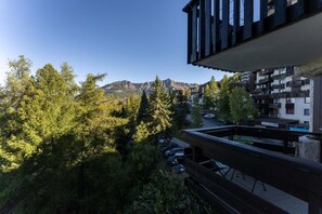 Un balcón con vistas a una montaña, árboles y un estacionamiento.