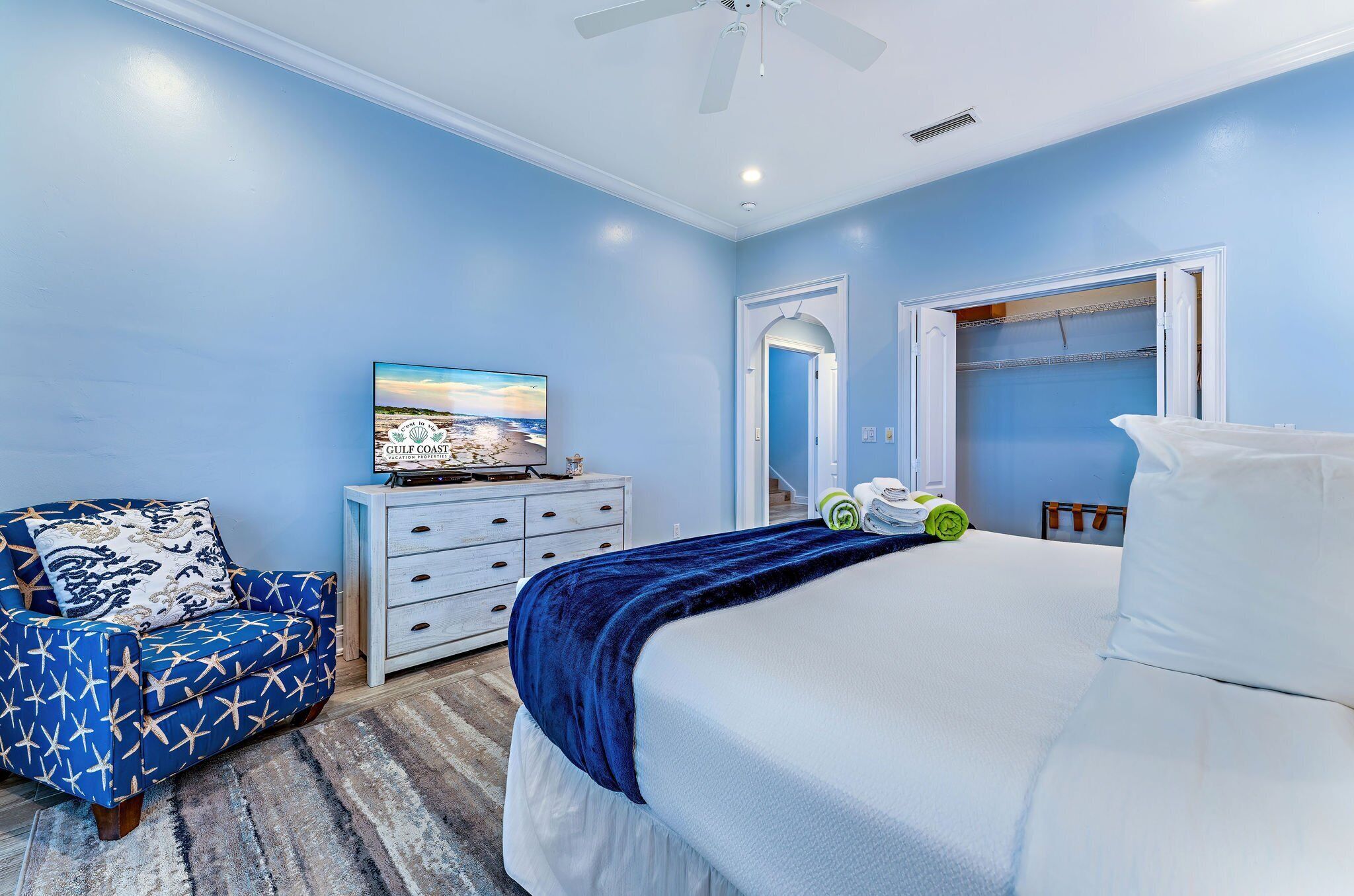 Une chambre à coucher avec un lit, une chaise, une commode et un tableau au mur.
