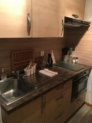 Une cuisine moderne avec des meubles en bois, un évier en acier inoxydable et un four encastré.