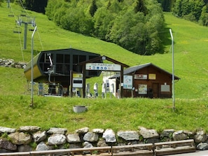 A mountain lodge with a ski lift, a signboard, and a wooden cabin.