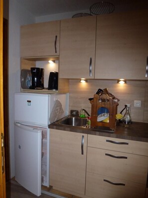 A compact kitchen with wooden cabinets, a white refrigerator, a sink, and a coffee maker. - Wifi, 2nd floor, parking, tv, ski locker, 26m², Arêches-Beaufort (Beaufort)