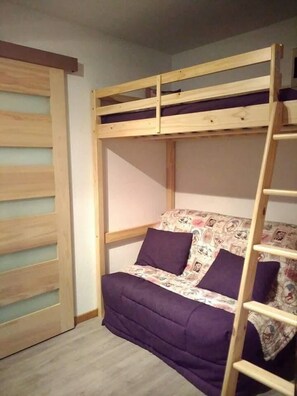A bunk bed with a wooden ladder, a purple mattress, and a floral-patterned blanket. - Wifi, 2nd floor, parking, tv, ski locker, 26m², Arêches-Beaufort (Beaufort)