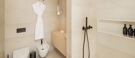 A modern bathroom with a toilet, bidet, and a shower area.