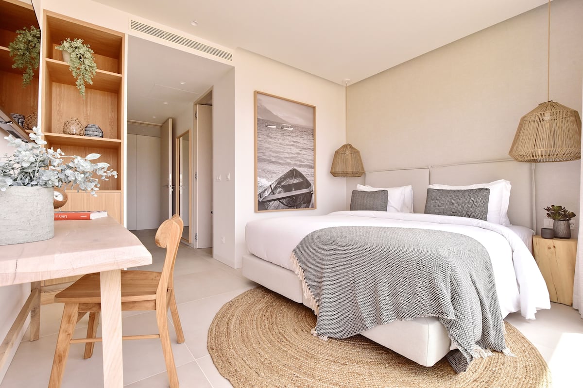 Un dormitorio moderno con cama, mesitas de noche, un escritorio y una silla.