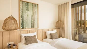 A hotel room with two beds, a large window with curtains, and a framed artwork on the wall.