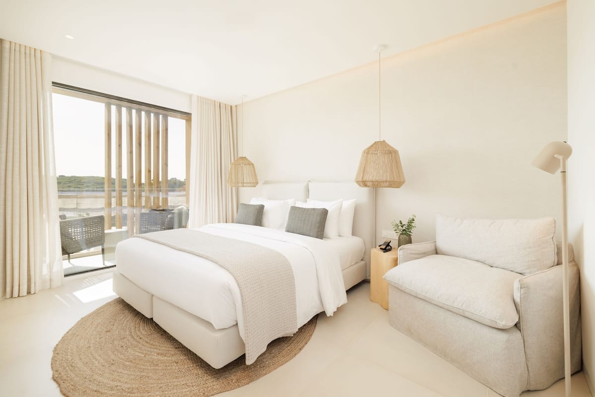 Un dormitorio moderno con una cama grande, un sofá y una mesita con una planta.