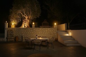 An outdoor patio with a stone wall, a table with chairs, and a staircase.