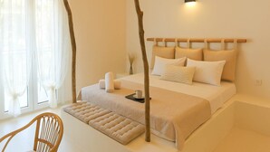 Quarto com cama, mesa de cabeceira, cadeira e janela com cortinas.