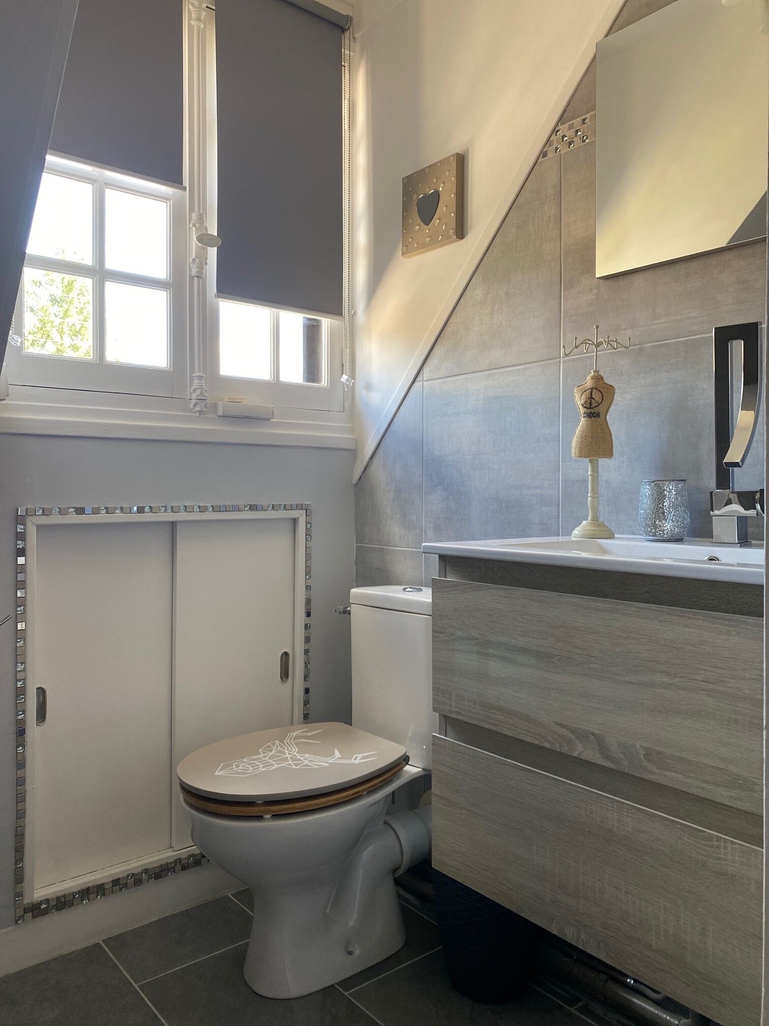A modern bathroom with a toilet, vanity, and a window above the sink.