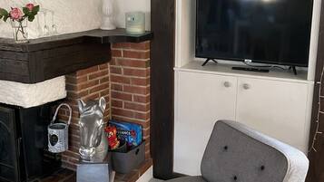 A living room with a fireplace, a television mounted on the wall, and a grey armchair.