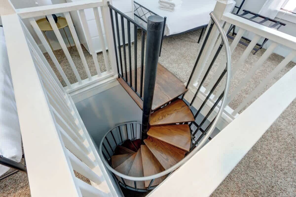 A spiral staircase with a white railing and a wooden finish.