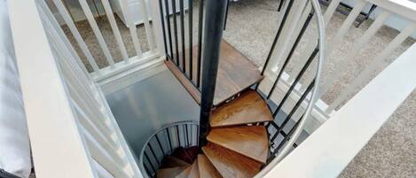 A spiral staircase with a white railing and a wooden finish.