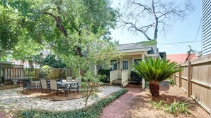 A backyard with a patio, outdoor furniture, a small tree, and a wooden fence. - The Tea Olive Cottage, Quaint | Pet-Friendly! (Savannah)