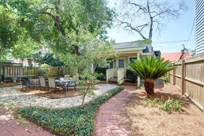 A backyard with a patio, outdoor furniture, a small tree, and a wooden fence. - The Tea Olive Cottage, Quaint | Pet-Friendly! (Savannah)