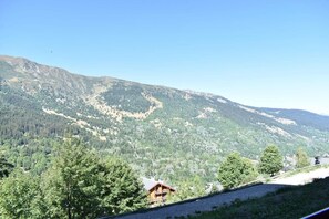 Un paysage de montagne avec un chalet en bois et un ciel dégagé.