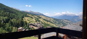 A mountain village with traditional buildings, a winding road, and a cable car in the valley. - 200m from ski slopes, 3rd floor, view ski slopes, balcony, tv, ski locker, 13m², Valmorel (Valmorel)
