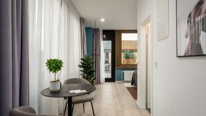A modern, well-lit room with a dining table, chairs, and potted plants.