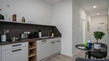 A modern kitchen with white cabinets, a dark countertop, and a dining area with a table and chairs.