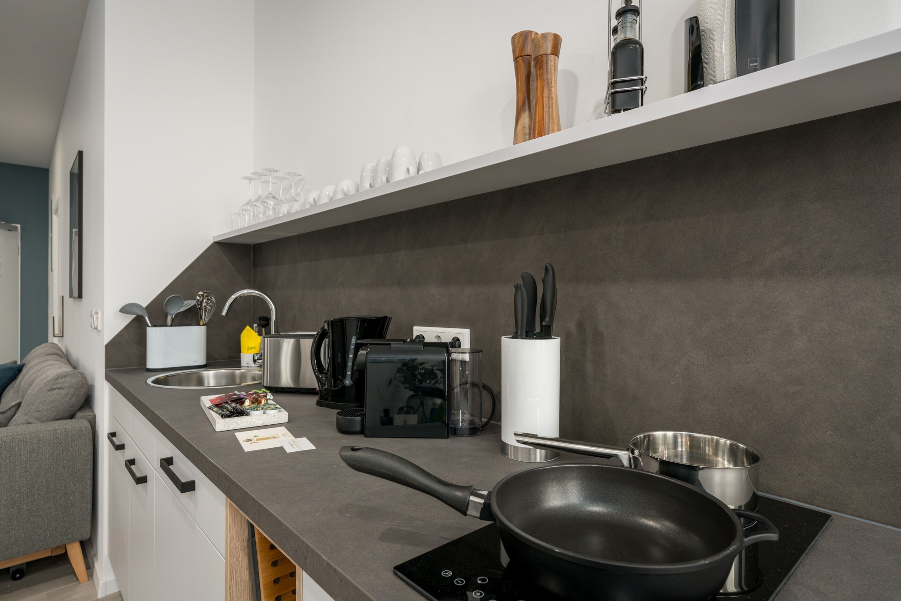 Eine moderne Küche mit Einbauherd, Kaffeemaschine und verschiedenen Küchenutensilien.