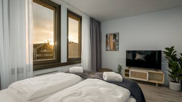 Ett modernt hotellrum med en stor säng, en tv och utsikt över stadsbilden genom fönstret.