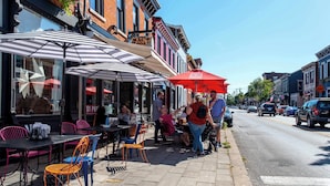 A sidewalk cafe with outdoor seating, tables, and umbrellas. - Covington Charm Suites (Covington)