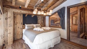 A wooden cabin-style bedroom with a large bed, a wooden ceiling, and a window with curtains. - Chalet, wifi, sauna, terrace, fireplace or stove, parking, tv, ski locker, 150m², Val d'Isère (Val-d'Isère)