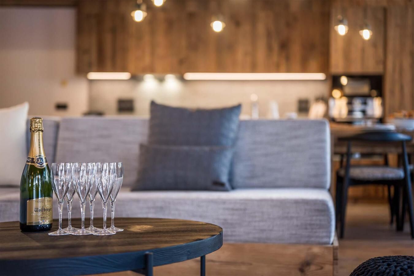 Un salon moderne avec une table en bois, une bouteille de champagne et plusieurs verres.