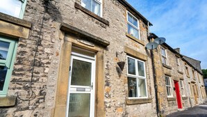 A stone building with a white door, a red door, and a satellite dish. - Stonelea (Tideswell)