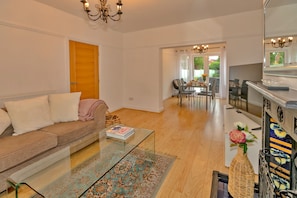 Uma sala de estar com sofá, mesa de centro e um espaço de jantar com cadeiras e mesa.
