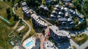 Vista aérea de una zona residencial con varias casas, una piscina y un camino sinuoso.