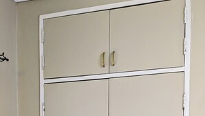 Une armoire fermée à deux portes, avec une petite poubelle placée à côté.