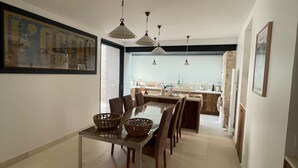 Una cocina moderna con comedor, que presenta una mesa larga, sillas e iluminación colgante.