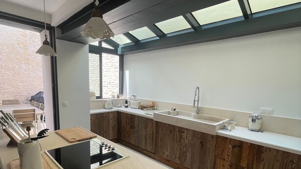 Una cocina moderna con armarios de madera, estufa integrada y un ventanal amplio.