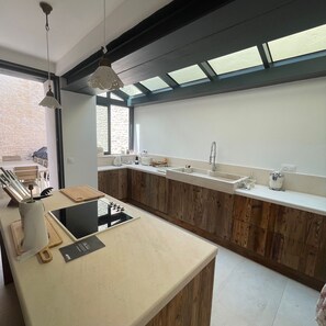 A modern kitchen with wooden cabinets, a built-in stove, and a large window.