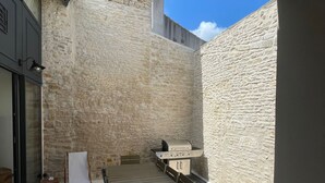 Un patio con mesa y sillas, una parrilla y un muro de piedra.