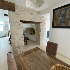 A dining area with a wooden table and chairs, a stone wall, and a ceiling light fixture.