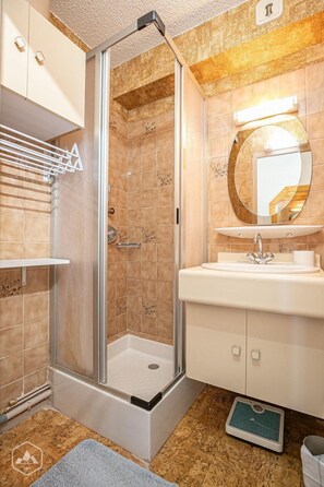 Enjoy a refreshing shower with a clear view of the floor in this bathroom, featuring a glass-enclosed shower, a vanity with a round mirror, and a single faucet.