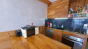 A compact kitchen with wooden cabinets, a microwave, a toaster, a coffee maker, and a dishwasher.