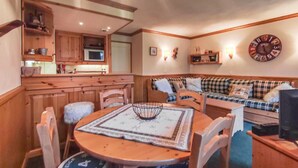 A cozy room with a wooden dining table, chairs, a sofa, and a kitchen area. - 100m from shops, 2nd floor, view ski slopes, balcony, ski locker, 39m², Valmorel (Valmorel)