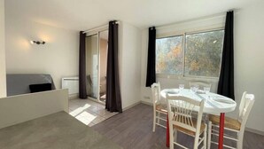 A modern room with a dining table, chairs, a sofa, and a sliding glass door leading to an outdoor area.