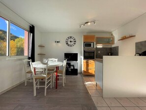 A modern kitchen with a microwave, oven, and a large clock on the wall. - 200m from resort center, 1st floor, balcony, tv, 29m², Serre Chevalier (Briançon)