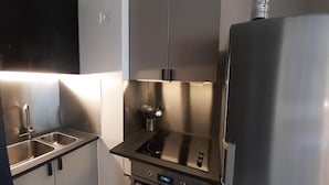 Una cocina compacta con electrodomésticos de acero inoxidable, incluyendo estufa, horno y refrigerador.